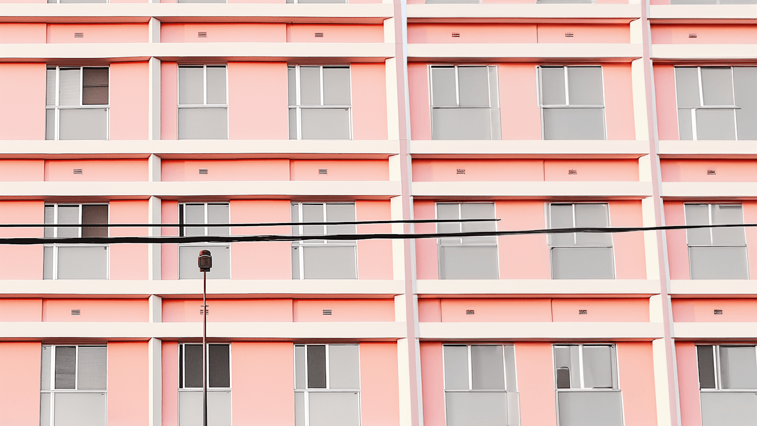The rose-pink facade of Rosa Chambers, a regular grid of white bands and grey glazed windows.